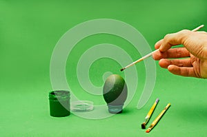 Man hand paints Easter egg with brush