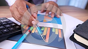 Man hand with pen analyzing bar chart on paper