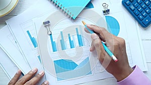 man hand with pen analyzing bar chart on paper