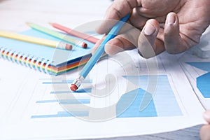 man hand with pen analyzing bar chart on paper