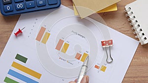 man hand with pen analyzing bar chart on paper