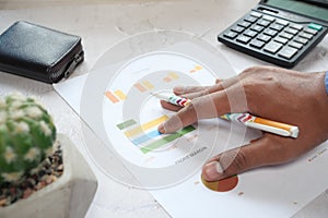 man hand with pen analyzing bar chart on paper