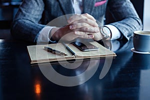 Man hand with pen writing on notebook on table. Man working at coffee shop.