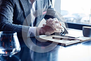 Man hand with pen writing on notebook on table. Man working at coffee shop.