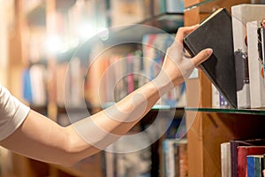 Man hand picking a book from bookshelf