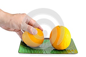 Man hand picking one oranges on plate with clipping pat