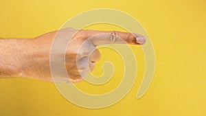 Man hand is pointing at something or someone isolated on yellow background. closeup