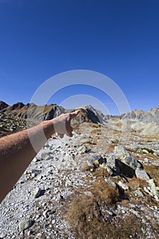 Man hand is pointing at the top and peak of the mountain.