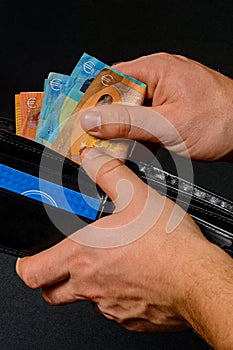 Man hand pulling money from wallet, black background and black wallet