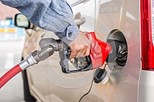 Man hand pumping gasoline with insect on car lights