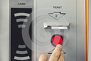 Man hand pushing red button to recieve ticket at car parking entrance. Ticket printing terminal machine with wireless card access photo