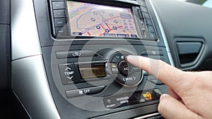 Man hand pushing temperature car unit control - dual climate - ac vents and navigation display