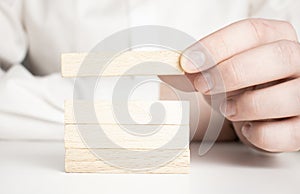 Man hand put wooden blocks in the shape of a staircase isolated on white background with copy space. Concept of building success