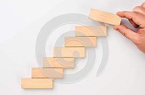 Man hand put wooden blocks in the shape of a staircase