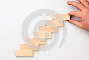 Man hand put wooden blocks in the shape of a staircase