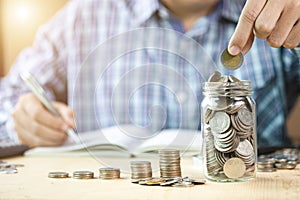 Man hand putting coin to jar with stacking  coin for growth business and saving investment concept