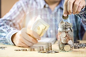 Man hand putting coin to jar with stacking  coin for growth business and saving investment concept