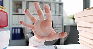 Man hand reaches out from under table on which lot of business documents lie