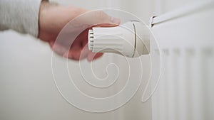 Man hand regulates temperature knob of heating radiator for heating room