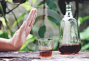 Man hand rejecting glass with alcoholic beverage on table outdoors background - refuses to drink a alcohol whiskey