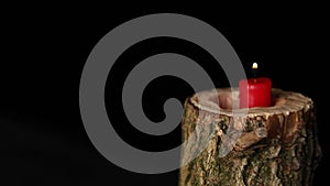 Man hand set on fire on candle in wooden candlestick black background