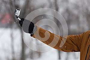 Man hand shoot by the small camera in deeply snow. Nature, storm in the urban park. Outdoor activity.