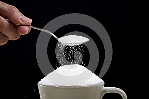 Man hand with spoon pouring a crazy lot in full coffee cup in addiction concept