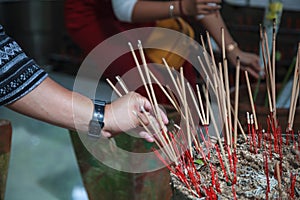 Man hand sticks burning incense in incense pot in Buddhist Temple. Buddhism, Asian traditional religious ceremony, Rituals, Making