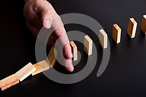 Man hand stop domino falling effect on black background