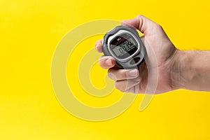 Man hand with stopwatch on a yellow background, closeup. Concept of sports.