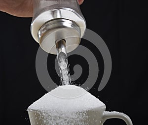 Man hand with sugar bowl pouring a crazy lot in full coffee cup in addiction concept