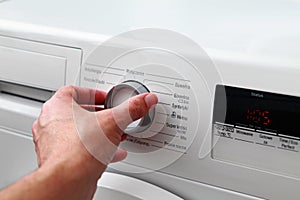 Man hand switches on washing machine