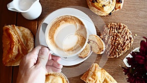 Man Hand Take Cup of Coffee on Breakfast with Croissants on Wooden Table in Cafe