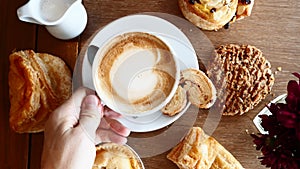 Man Hand Take a Cup of Coffee from Wooden Table with Baked Pastry, Breakfast