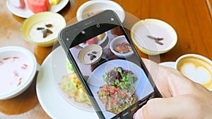 Man hand take photos of breakfast by mobile phone