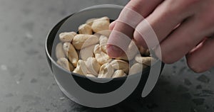 Man hand takes cashew nuts from black bowl on terrazzo countertop