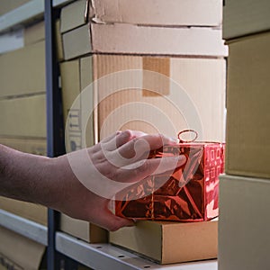 A man hand takes a gift box in the store warehouse for delivery on Christmas Eve on New Year Eve