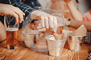 Man hand takes snacks crackers, croutons with sauce and drinks beer in pub bar at wooden table