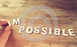 Man hand taking of the letters in from the word imposible so it says possible