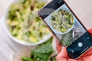 Man hand taking photo alternative vegetable zucchini pasta by mobile phone.