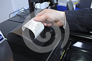 Man hand taking the receipt from printer of the cash recycler working