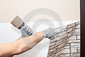 Man hand tear off old light wallpaper from wall.Preparing for home repair work.removing Wallpaper with a spatula, the