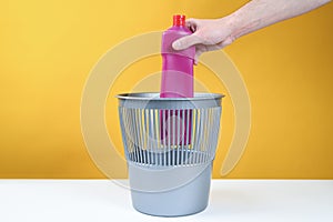 Man hand throwing a empty plastic water bottle into the trash can