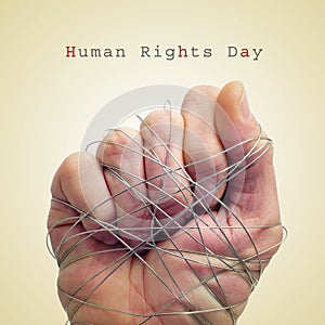 Man hand tied with wire and the text human rights day