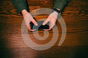 Man hand touch on a screen of mobile phone on a wooden table. Business situation.