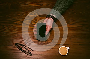 Man hand touch on a screen of mobile phone on a wooden table. Business situation.