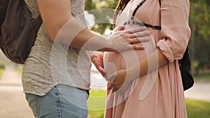 Man hand touching belly of his pregnant woman standing on street, closeup view.