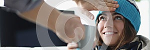 Man hand touching forehead of sick woman in hat and giving cup of tea