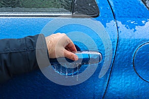 Man hand trying to open freezing car door handle, Hand on Car`s door handle after a freezing rain
