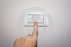 Man hand is turning on or off electrical light switch